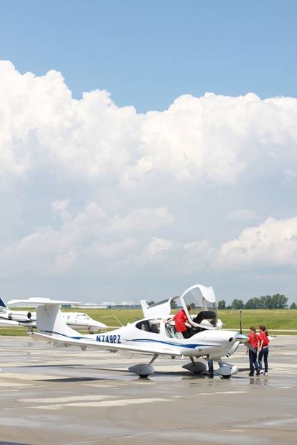 campers surrounding a small airplane on an airstrip